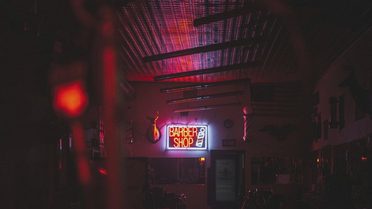 Interior de una barbería en penumbra con el rótulo luminoso encendido